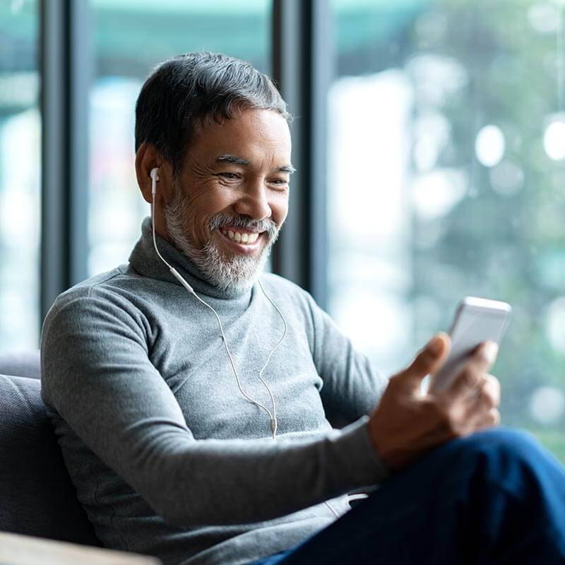 smiling man with ear buds in looking at his phone